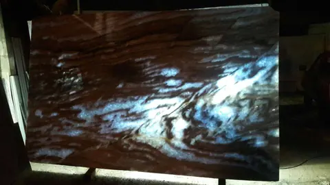 Chapa de mármore translúcido iluminada à noite, em tons de azul e marrom